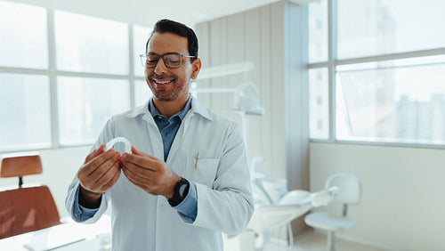 Male dentist examines orthodontic model in modern dental clinic
