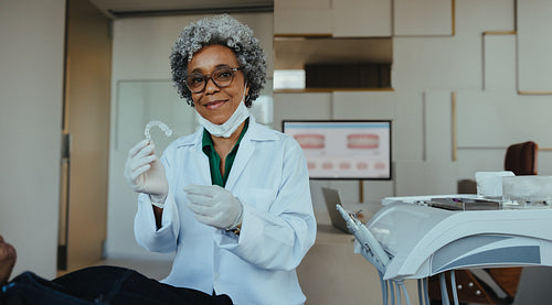 Dentist showcasing clear aligner in modern dental clinic