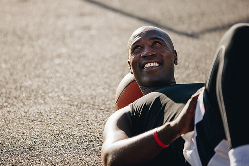 Man lying on ground with basketball under his head
