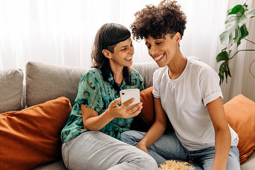 Two lesbian lovers using a smartphone together at home