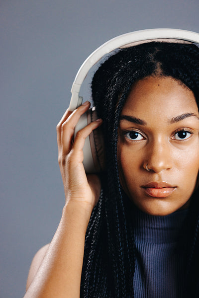 Portrait of a young woman listening to music on wireless headphones in a studio