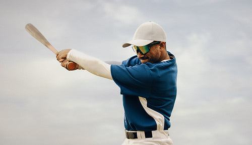 Determined baseball player swinging bat with focus