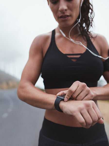 Fitness woman adjusting smart watch while exercising outdoors