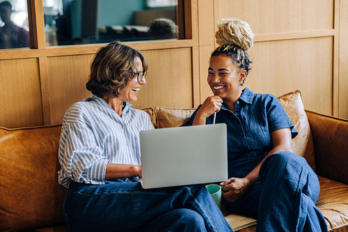 Two women enjoying time together with a laptop on a couch