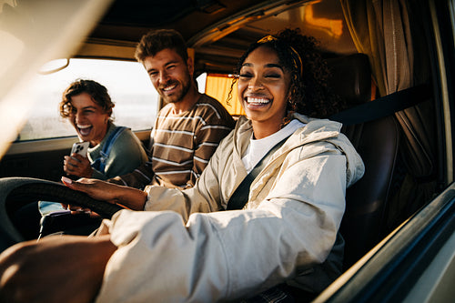 Happy friends ride in a car, laughing and enjoying a road trip