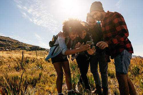 Young people hiking in countryside using mobile phone