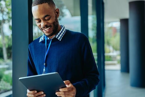 Confident African businessman working on tablet in the office corridor