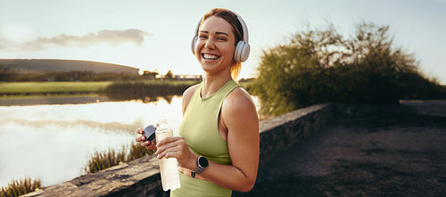 Woman taking a break from exercise by a lake at sunset
