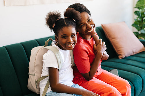 Mom and daughter smiling and sitting on the couch on a school morning