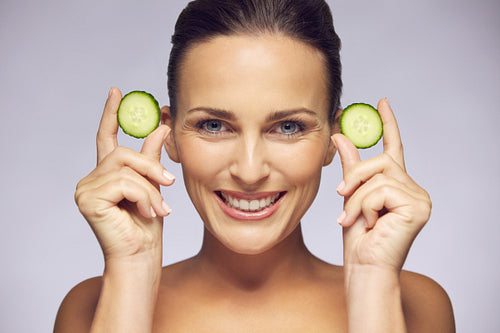 Young beauty smiling with cucumber slices