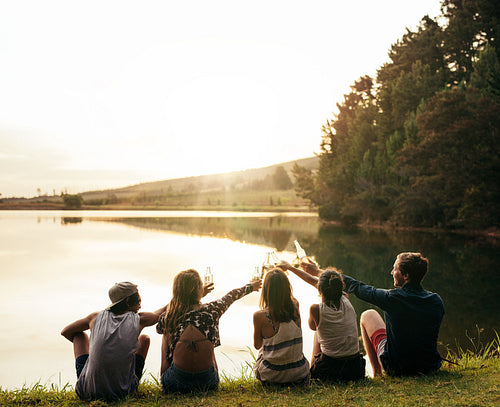 Friends toasting and celebrating with beers at the lake