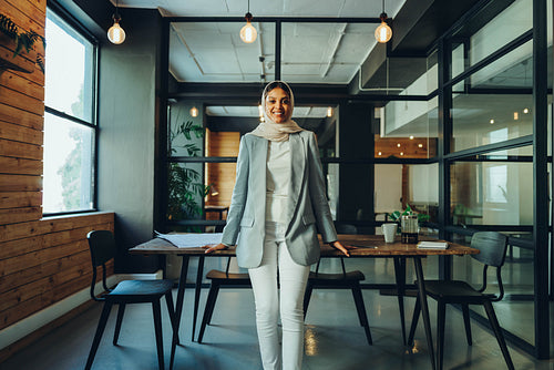 Happy Muslim entrepreneur standing in an office boardroom