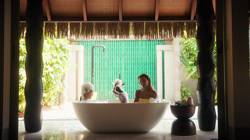 Mother and children enjoy a playful bubble bath during their luxury resort vacation