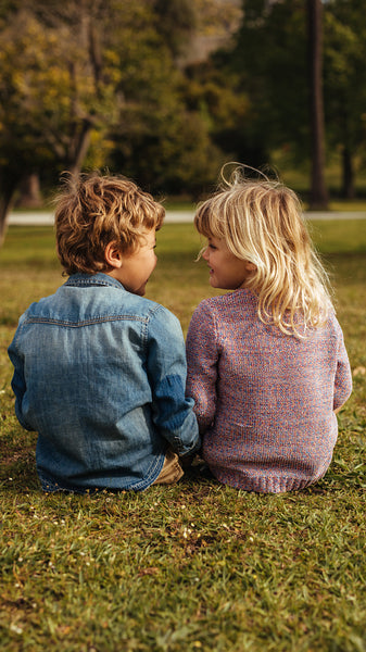 Siblings sitting on the grass and looking at each other