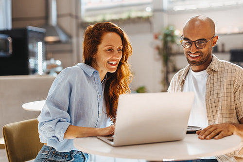 Teamwork in a cafe: Two business professionals using a laptop during a business lunch