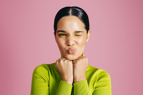 Vibrant glamour: Woman with graphic eyeshadow winking at the camera in a studio