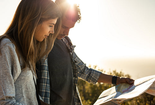 Tourist couple using a map to find the route on hike