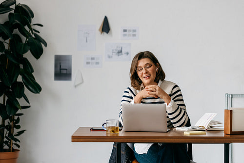 Woman working on laptop in home office during remote work video call