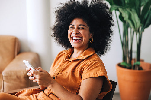 Female entrepreneur smiling happily while holding a smartphone