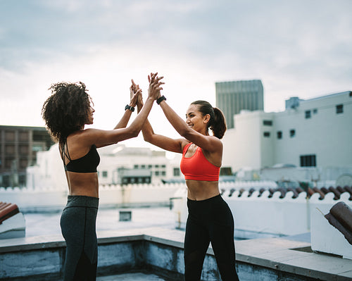 Cheerful women athletes giving high five during workout