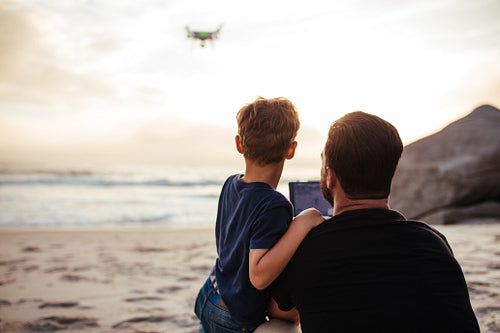 Father and son flying drone at the beach