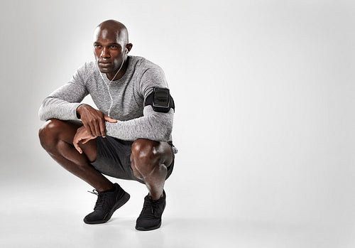 Young african man crouching on grey background