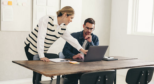 Two business colleagues working with a laptop in an office