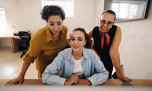 Three businesswomen collaborate on a project at a modern office workspace