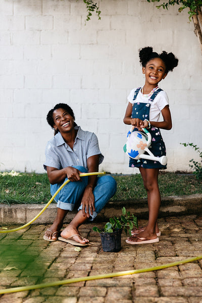 Mother and daughter gardening and laughing together outdoors