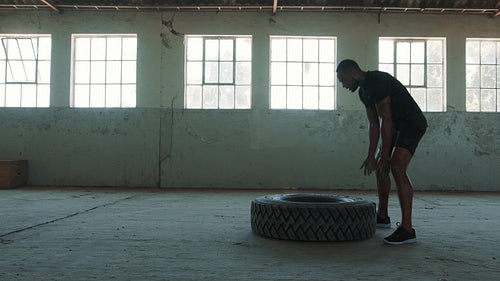 Sportsman flipping tyre at cross training club