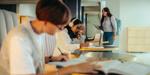 High school students studying in a modern study centre, focused on learning with books and laptops