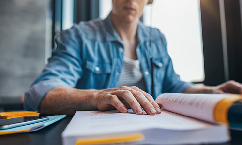 Young man reading book at library
