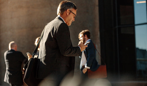 Man using mobile phone while walking to office