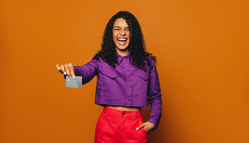 Cheerful woman paying with contactless card on orange background