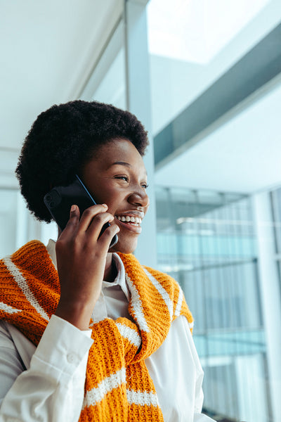 Confident professional African woman in fashion industry smiling while talking on phone