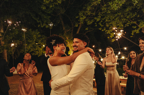 Newlywed couple celebrates with guests at an outdoor nighttime wedding reception