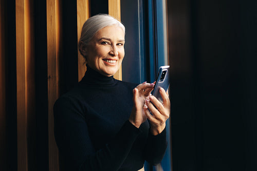 Working the modern way: Senior woman using smartphone for business