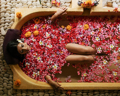 Woman taking flower bath at spa center