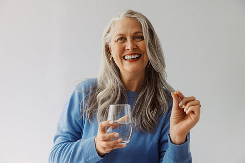 Senior woman takes vitamins with water for healthy aging