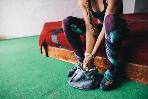 Woman wall climber coating hands with gripping powder
