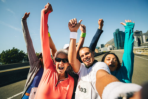 Group of runners celebrating their race success together outdoors with a selfie