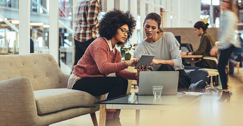 Female coworkers discussing work in office