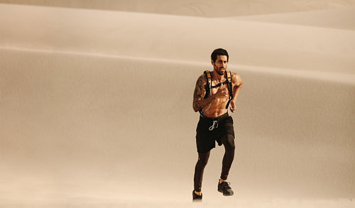 Fitness man running on sand dunes