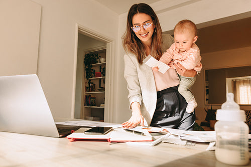 Mom holding her baby while working in her home office