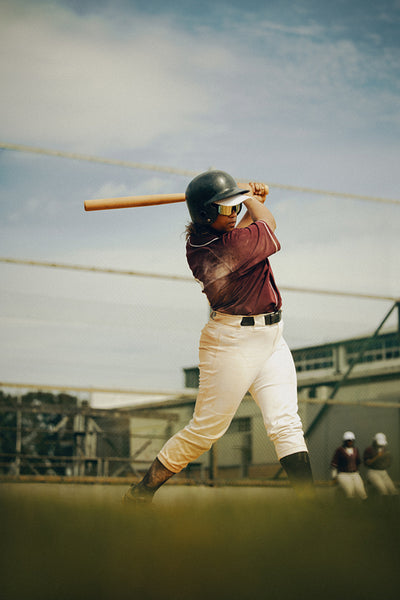 Focused baseball player swinging bat during outdoor practice session on a sunny day