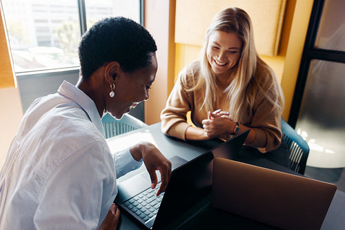 Two women discussing ideas and smiling during a professional meeting