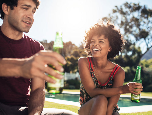 Happy young couple sitting outdoors with beers