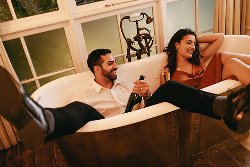 Smiling couple having champagne in a bathtub