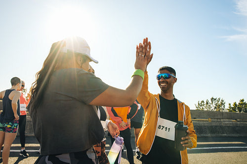 Runners sharing a high five during a sunny marathon event