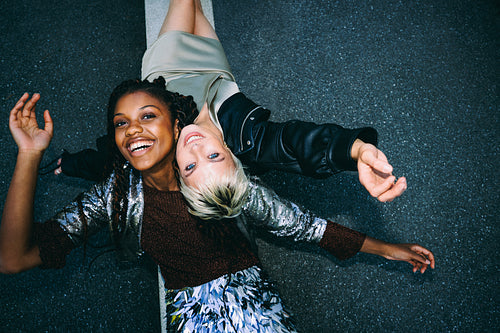 Laughing woman lies with friends on urban pavement